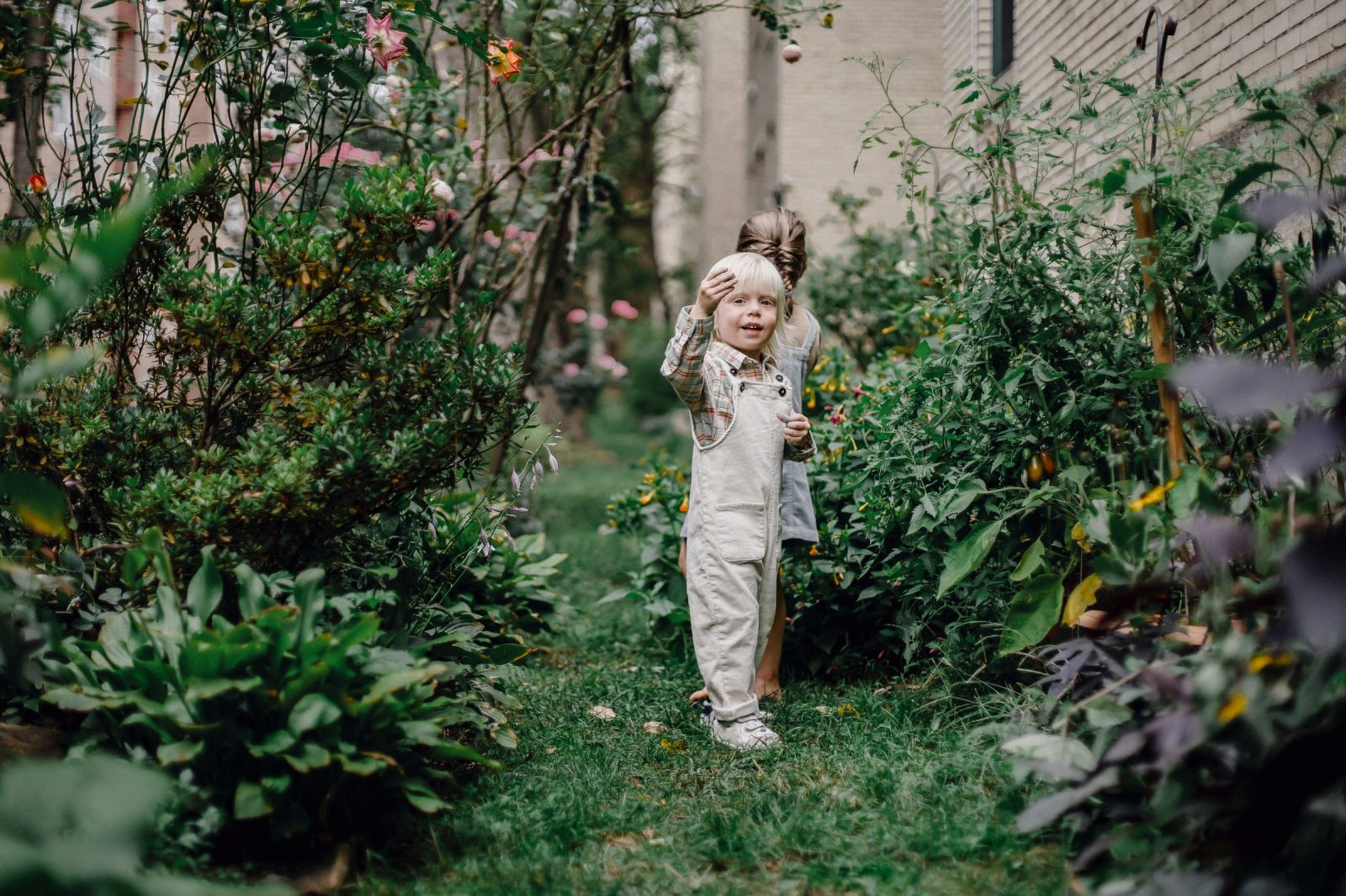 Zwei Kinder spielen im umzäunten Garten eines Familienhauses während eines Ferientauschs